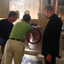 CUA student Matthew Hoffman, carpenter Deacon David Cahoon, and Basilica Rector Monsignor Walter Rossi discuss placement of a mosaic on the altar.