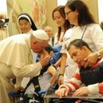 Pope Francis embraces a man in a wheelchair.
