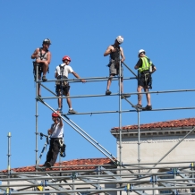 Workers building the 10-level media riser construct the top tier.