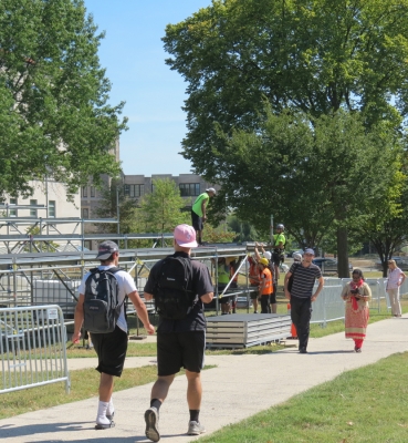 Students walk through fencing on the University Mall past the media riser under construction.