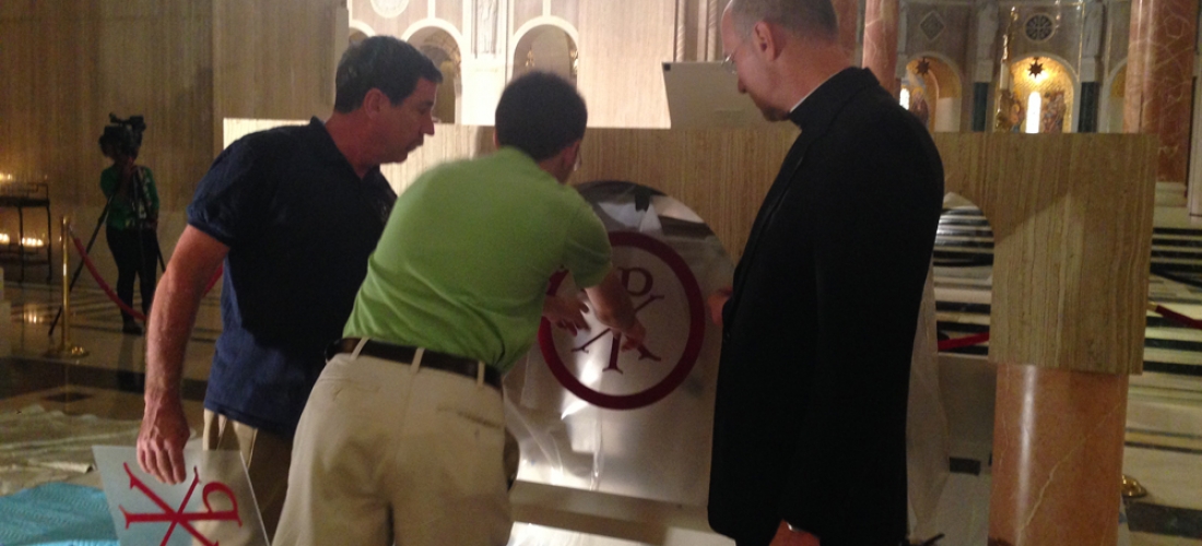 CUA student Matthew Hoffman, carpenter Deacon David Cahoon, and Basilica Rector Monsignor Walter Rossi discuss placement of a mosaic on the altar.