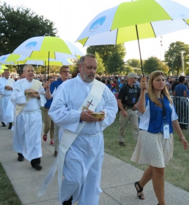 Deacons, accompanied by student volunteers, process to distribute communion.