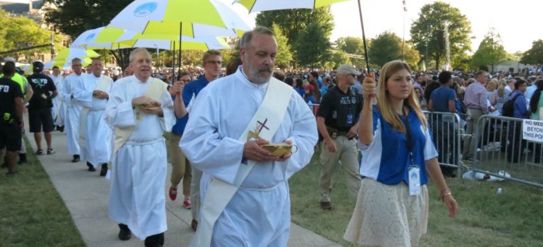 Deacons, accompanied by student volunteers, process to distribute communion.